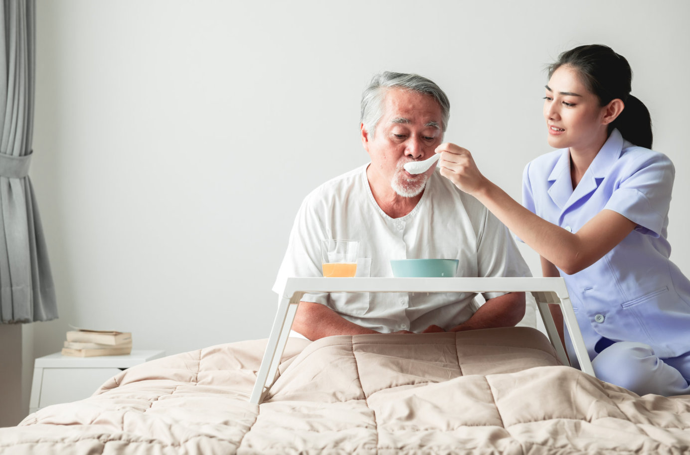 female caregiver feeding food to senior man